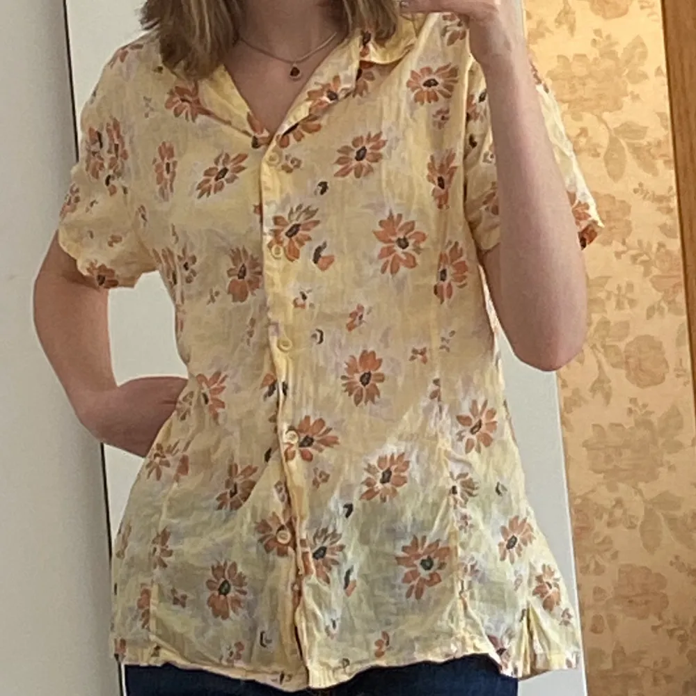 Gul kortärmad skjorta i blommigt tyg, oklart vilken storlek men jag är xs för preferens så den passar nog stötte personer än mig med eftersom den är  oversized på mig:). Skjortor.