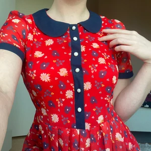 Röd blommig klänning - Jättesöt blommig klänning, med dragkedja i ryggen och två små fickor i kjolen.