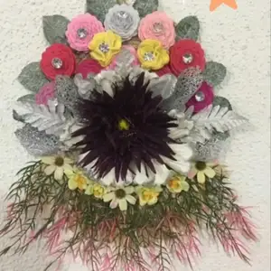blommor i olika färger gjorda av filt.  Den är dekorerad med kristallstenar i mitten.