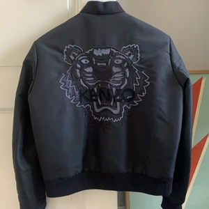 Svart bomberjacka från Kenzo - Svart bomberjacka limited edition från Kenzo. Inköpt i Paris för cirka fyra år sedan men säljer nu på grund av att jag inte använt den. Nypris cirka 4000 kronor.