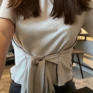 Beige topp med fina detaljer, knyte - Säljer min fina beiga blus/topp från Zara med knyte där fram som man själv justerar. Toppen är använd ett antal gånger men är i ett superfint skick och den känns fortfarande som ny! Köparen står för frakten! BUDA FRÅN 100kr. Kontakta mig vid funderingar eller liknande💕💕