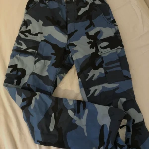 Cargobyxor - Blåa cargobyxor med camouflagemönster! Köpta på Junkyard och endast använda ett fåtal gånger. Kan mötas i Stockholm 💓