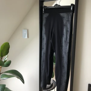 Träningstights från H&M - Svarta tights med silvrigt ormskinsmönste på sidorna. Köpta nyligen och oanvända, storlek S.