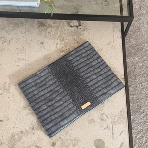 Datorfodral Bianca ingrosso  - Ett sparsamt använt datorfodral från Bianca Ingrossos märke. Den är mörkgrå med snakeprint och gulddetaljer. Skicka meddelande för fler bilder samt information! Nypris var 599kr, säljer för 200kr