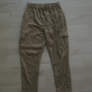 Beige byxa med knyte s. S - Svin coola byxor från Nelly i ett jätteskönt luftigt material med fickor på sidorna. Använt ett flertal gånger men fortfarande i bra skick!🤎