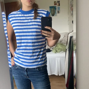 Randig t-shirt  - Randig t-shirt med detalj vid axeln. Har ingen utsatt storlek men gissar på S. 