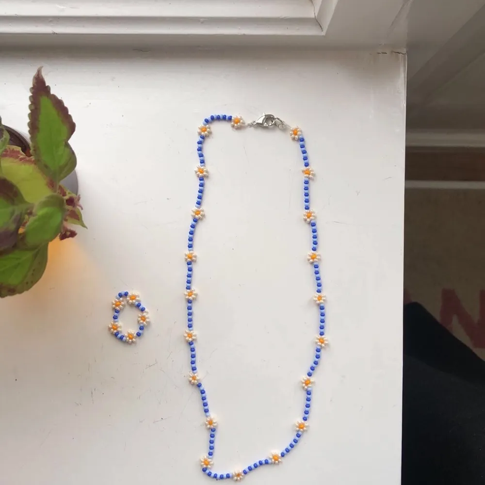 Handgjordast halsband med matchande ring i två nyanser av blått med blommor i pärlemor. Standardspännen på halsbandet. Frakt ingår i priset <3. Accessoarer.