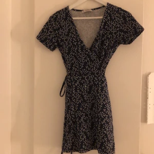 Wrap tie klänning storlek XS/S - Supersöt sommarklänning från Pull&bear. Storlek M men skulle mer säga XS/S. Färgen är mörkblå med vita blommor. Köparen står för frakt.