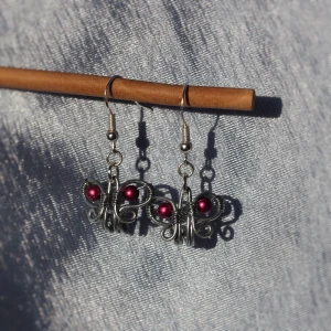 Små Fjäril Örhängen🦋 - GRATIS FRAKT. Ett par jättegulliga örhängen formade som fjärilar, egentillverkade. Pärlan är lila men kan göra i massa olika färger, kolla min profil för varianter på dessa. Krokarna är nickelfria. Kan fraktas eller mötas upp i Stockholm/Huddinge. Skriv vid frågor!!