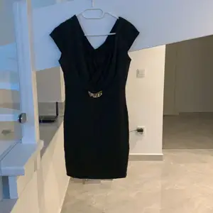 En svart klänning med guld detalj vid midjan
