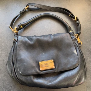 Marc Jacobs Classic lil ukita - Axelremsväska från Marc by Marc Jacobs modell: Classic Q Lil Ukita.  Fint skick. Skinnet är i fint skick även om den är väl använd. Det finns en del skav på de guldiga detaljerna. Innerfodret är lite smutsigt men kanske kan rengöras. Väskan är använd men i det stora hela i fint skick. Dustbag följer med. Mått på väskan Bredd: 30cm, höjd: 25cm, djup: 10cm.