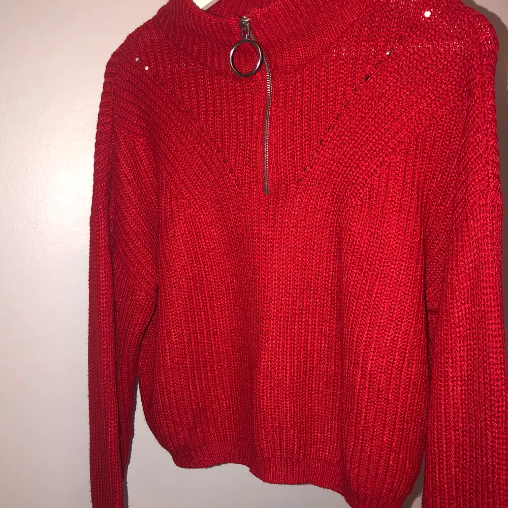 En röd stickad tröja med en drag kedja vid halsen som går att dra ner och upp. Tröjan är andvänd två gånger och har legat i en garderob i två år helt orörd, så den är i ett bra skick.. Stickat.