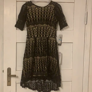 BEIGE KLÄNNING MED SVART SPETS STL 32-34 - Jätte söt beige klänning med svart spets i storlek 32-34  . Klänningen är aldrig använd och har kvar prislappen. Budgivning startar på 100kr i komentarsfältet, köp direkt för 160kr! Köpare står för frakt. (budgivningen avslutas 1 april)