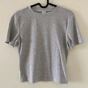 Grå t-shirt - Säljer denna gråa topp som är sparsamt använd. Toppen är mer åt det croppade hållet. Tröjan är i storlek M men skulle säga att den sitter mer som S Frakten ingår ej.