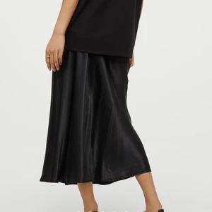 Helt ny & oanvänd satinkjol HM storlek M - Helt Ny och helt oanvänd satinkjol från H&M! Svart färg. Detaljer:  - slits Går att välja om man vill att slitsen ska vara på sidan, bakom eller framifrån.  Resår i midjan. Storlek M, medium.  Ej genomskinlig. Nypris 250 kr. Frakt tillkommer.