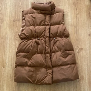 Brun dunväst - En brun dunväst med dragsko i midjan. Strl S/M. Aödrog använd, endast hängt i garderoben. Köpren står för frakten