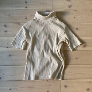 Kortärmad polotröja - Kortärmad, ribbad polo i beige/gräddvit. Väldigt luftig och sitter skitsnyggt och bekvämt.