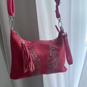 Rosa super söt väska - Super fin och söt rosa väska med vingar av ”diamanter”. Den har skjusterbara band och flera fickor!