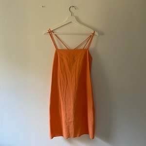 Snygg kort orange (mer är det pastelliga hållet) klänning i linne. Banden går att ha på olika sätt och den är insydd i midjan för att få en snyggare passform (syns inte på bilden men när man har på sig den) 🥰