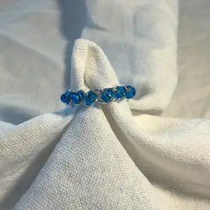 En hemmagjord ring med massor små blåa pärlor och metalltråden i färgen silver. Fin att ha till blåa, vita och beicha kläder.