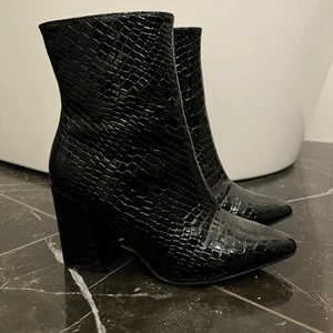 Stövletter stl 38 - Svarta stövletter i blank ormskinnsimitation stl 38. Använda 1 gång. Helt i nyskick. 
