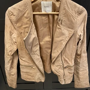 Jacka ifrån Mango strl XS - En jacka i fake skinn, beige i strl XS. Använd men i väldigt bra skick. 