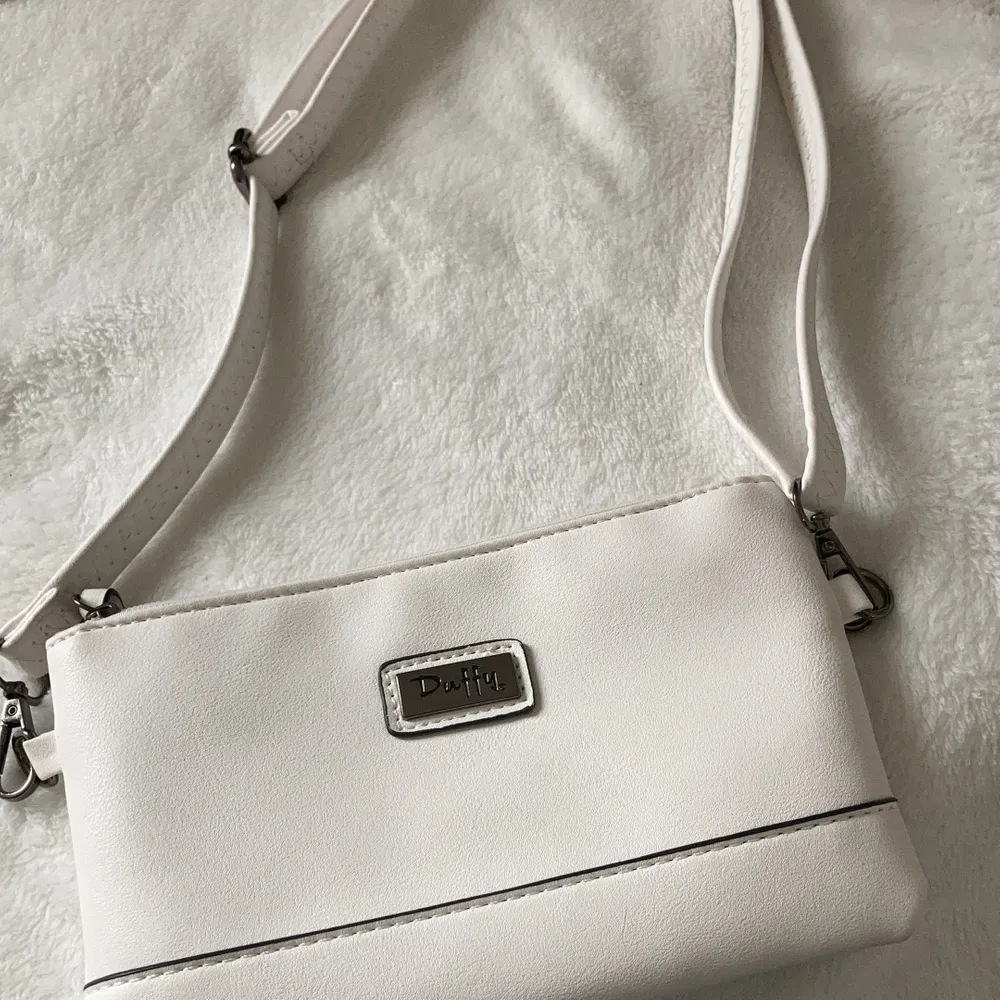 En vit Duffy väska med fickor både utanpå och inuti ( nypris 200kr ) det finns både ett kort band för handväska och ett långt band till axelväska💓 använd en gång. Väskor.