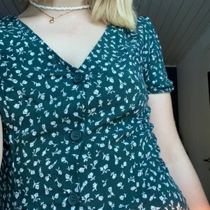Grön blommig klänning - Grön klänning med vita blommor 🌸 Från HM, använd typ en sommar. Jag är 162cm lång och jag tycker att den är på gränsen till för kort - absolut individuellt så skriv gärna om du vill ha mått osv 🥰