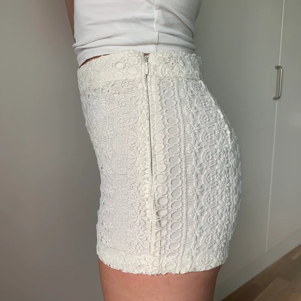 Ett par vita shorts med spets detaljer. Dragkedja på vänster sida för att få av och på. Shorts.