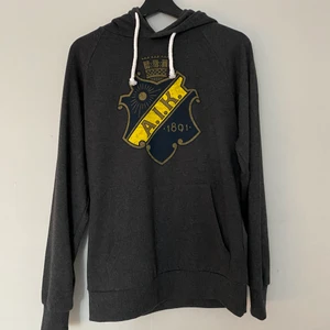 AIK shield Hoodie - Helt oanvänd hoodie köpt från AIKs internetshop. Säljer som sagt för att den ej kommer till användning. Köpt från herravdelningen storlek S men passar mig som är i storlek S. Frakt ingår ej i priset.