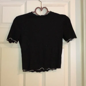 T-shirt  - Croppad svart T-shirt med vita sömmar kring hals,mage och armar