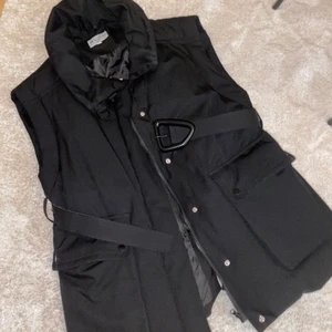 Fodrad väst, NA-KD - Svart fodrad väst från NA-KD, oversized i modellen. Kan bäras med ett medföljande bälte i midjan eller utan. Dragkedja och knappar fram, en hög krage som man kan välja att knäppa eller inte. 