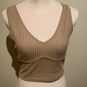 Beige/brunt linne  - Ett helt oanvänt beige brunt linne som har en detalj under brösten 