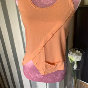 Topp - Osymmetriskt topp i en mjuk orange nyans med snygga detaljer 