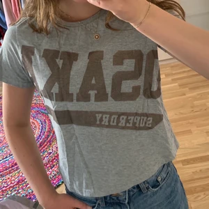 Grå t-shirt croppad - Boxy tee från superdry. Trycket är skrivet i en bronsig färg och är väldigt unikt. Ursprungspris var 349kr. Säljes pga inte min stil längre🌞🌞