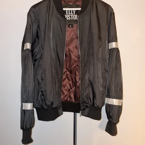 Bomberjacka elly pistol  - Säljer min snygga bomberjacka ifrån Elly pistol i Stl L unisex modell men upplever den liten i storlek! Den har två fickor, detaljer på armarna o på ryggen, fin vinröd/lila/brun insida 😍 använd endast nån enstaka gång!   250kr 