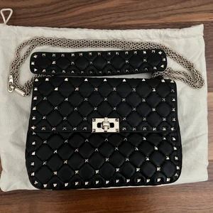 Valentino Rock stud bag - Intressekoll på min svarta Valentino väska Rockstud medium med guld detaljer.  Väskan är välanvänd men i väldigt bra skick förutom en slitningen vid ena bandfästet (går att fixa hos skräddare). Nypris på väskan är 20 000 kr men på grund av slitningen är mitt pris lägre.  För frågor eller rimliga bud är det bara att skriva :)   Bredd: 23 cm Höjd: 16 cm Djup: 7 cm