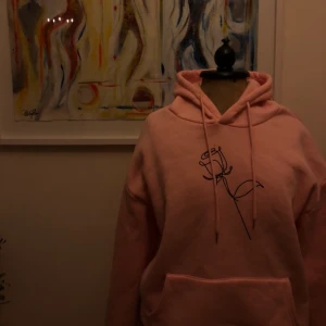 Rosa hoodie  - Stor rosa hoodie med en ros på! Köpt utomlands så vet ej vilket märke, men väldigt mysigt material på insidan. Säljer pga flyttning. Köparen står för frakt! 