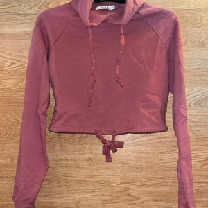 Croppad hoodie  - En croppad hoodie från NA-KD i mörkrosa, knyte längst ner! Storlek S! Hör av er vid frågor eller fler bilder💗