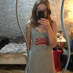 Svea klänning - Grå Svea klänning med röd text. Bra skick alldrig använd av mig (begagnad). Den slutar precis åvanför knäna (jag är 171cm lång). Den har slitsar på sidorna. 