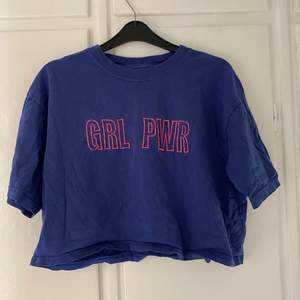 En blå croppad blå tröja med rosa text. Den är ifrån märket gildad. Storlek m. Köparen står för frakten :)
