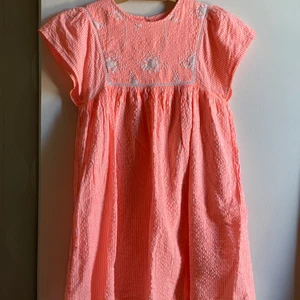 Korall färgad sommar klänning, köpt på Mango. - Klänningen är rätt så använd men ser i prensip fortfarande ny ut. Den är i storlek 152 (11-12 år). Klänningen är i en jätte fin korall färg, och är inte genomskinlig. För att den har en vit under skjol. Säljer den för att den har blivit för sliten. Köpt för 299kr