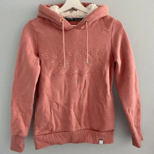 Rosa hoodie från Superdry - Nypris: 600kr. Rosa märkeshoodie från Superdry i bra skick! Ganska liten i storleken så skulle passa även en XS🩷