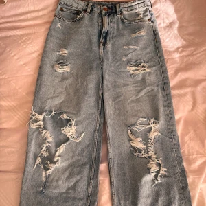  Jeans med hål -  Ett par välanvända jeans. Hålen som var från början har blivit större men inte överdrivet mycket!