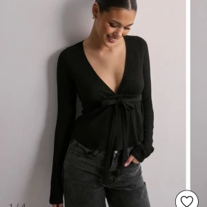 Svart ribbad omlottopp - Snygg svart ribbad omlottopp med långa ärmar och knytning i midjan. Perfekt för både vardag och fest, med en stilren och elegant look. Nypris 299 kr och jag aldrig använt denna ❤️