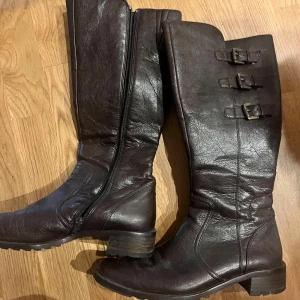 Bruna stövlar från Paul Green - Säljer ett par snygga bruna stövlar från Paul Green i skinn. De har en dragkedja på insidan och tre dekorativa spännen på utsidan. Perfekta för höst och vinter med en robust klack och slitstark sula. Passar både till vardags och lite finare tillfällen.