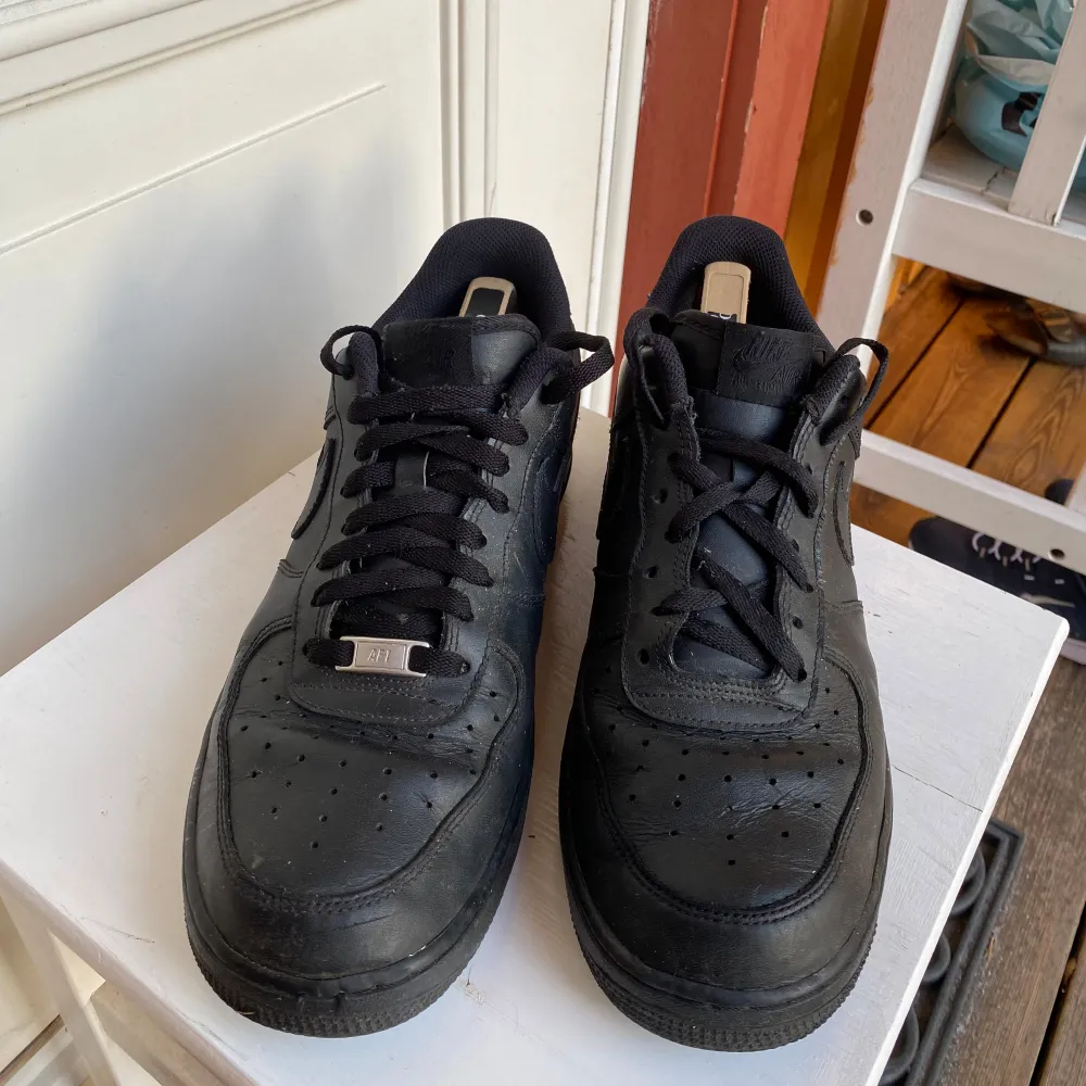 Säljer ett par klassiska svarta Nike Air Force sneakers i skinn. De är i bra skick med snörning och en stilren design som passar till allt. Perfekta för både vardag och fest. Storlek herr 45.. Skor.