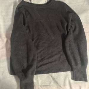 Mörkgrå stickad tröja - Säljer en mysig mörkgrå stickad tröja i bra skick. Perfekt för kyliga höst- och vinterdagar. Tröjan har långa ärmar och ribbade muddar vid ärmslut och nederkant. Superbekväm och stilren!