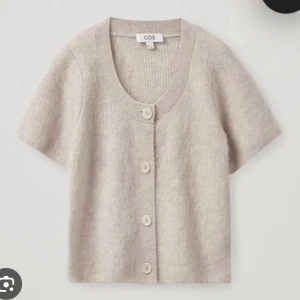 Beige kofta från COS - Säljer en superfin beige kofta från COS i mycket bra skick. Den är kortärmad och har stora knappar framtill. 