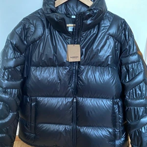 Svart pufferjacka från Burberry - Säljer en snygg svart pufferjacka från Burberry i nytt skick. Jackan är perfekt för vintern. storlek XL, fylld med gåsdun och fjädrar, originalpris 2150 eur.